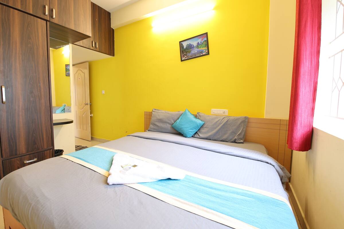 A bedroom with a bed, wooden wardrobe, and a painting on the wall.