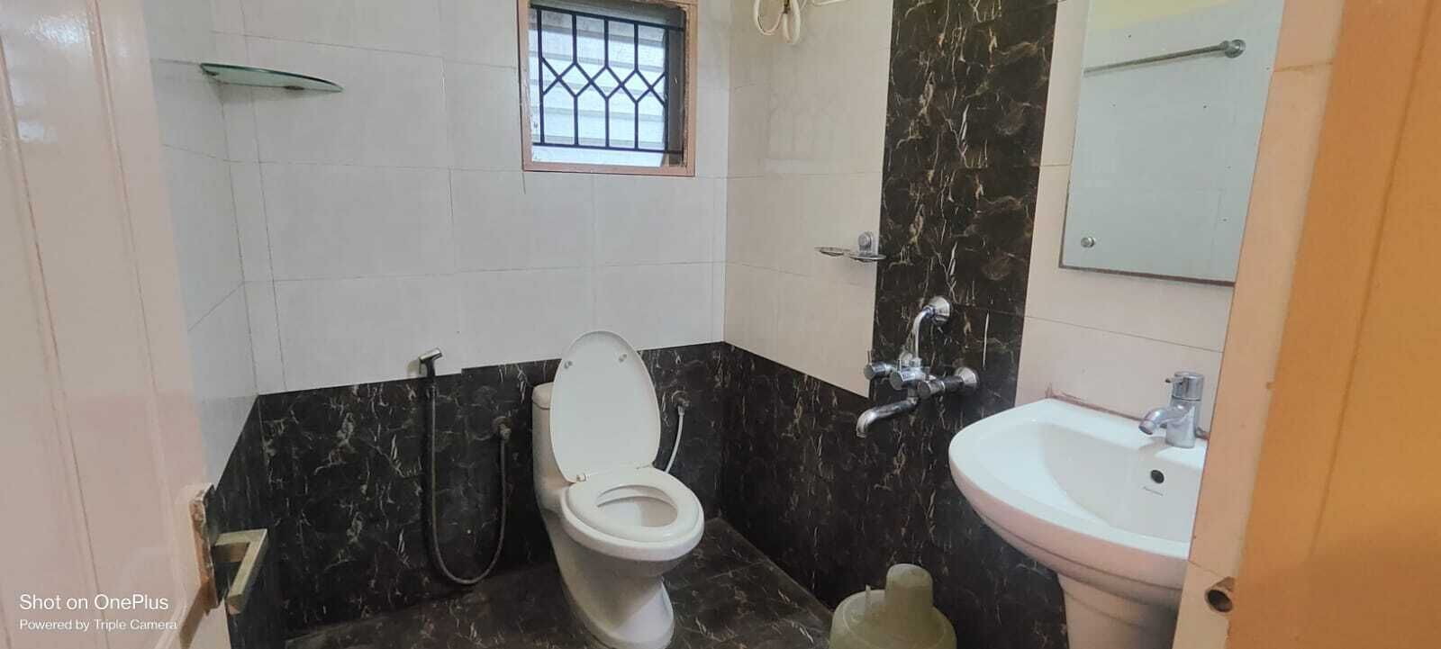 A bathroom with a toilet, a sink, a shower, and a small window.