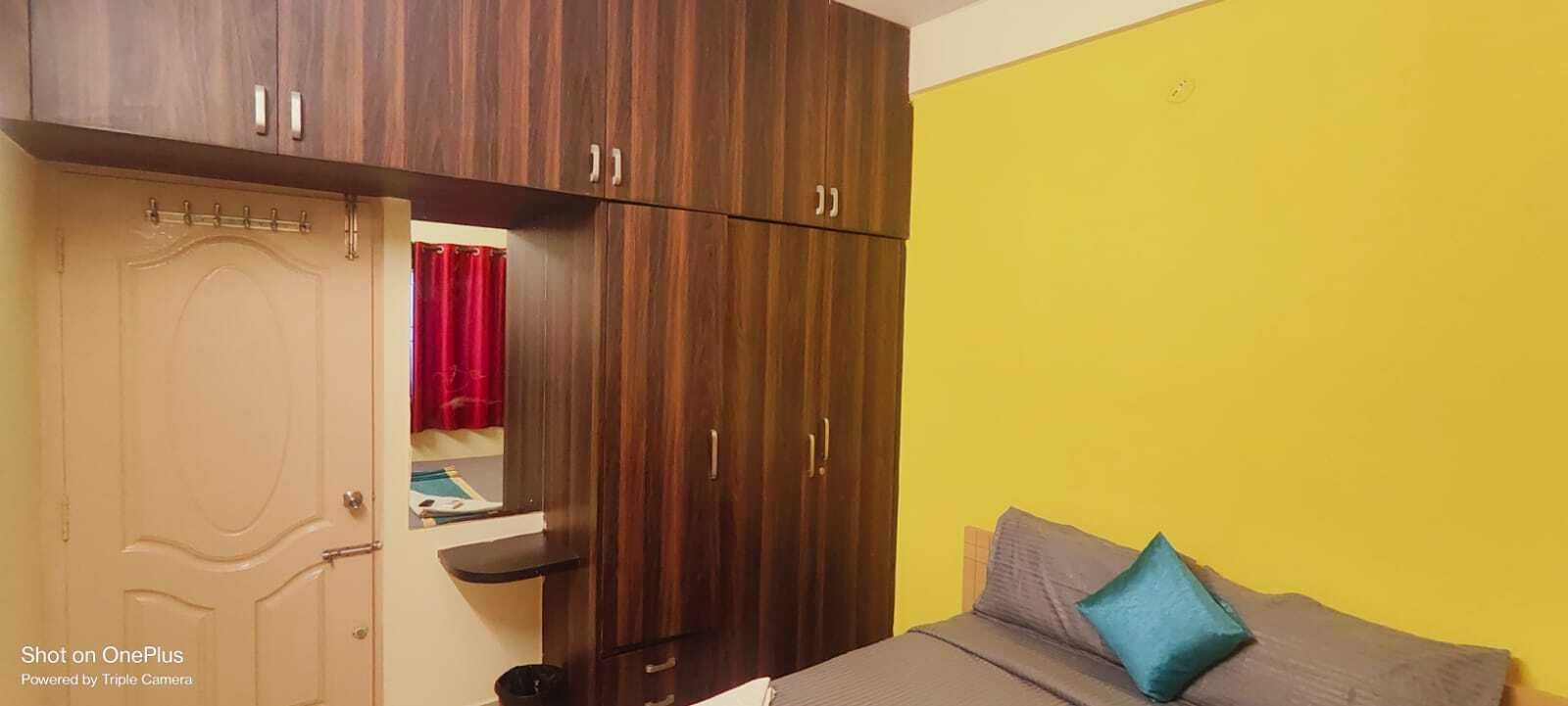 Un dormitorio con una cama, un armario y una pared amarilla.