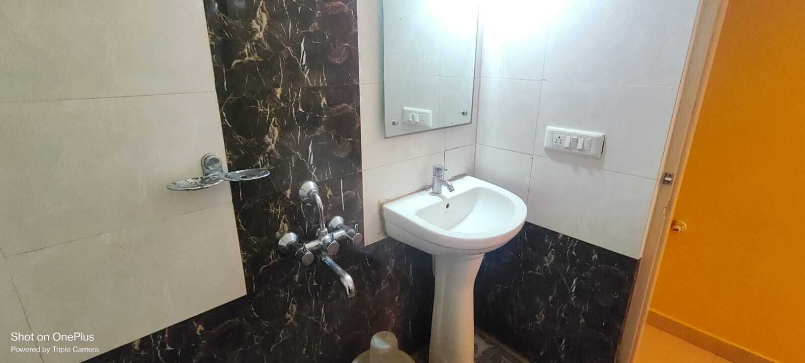 A bathroom with a white sink, a mirror, and a marble backsplash.