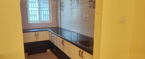 A kitchen with black countertops, white cabinets, and a window with decorative glass.