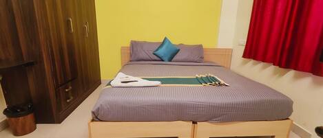 A room with a bed, wooden wardrobe, and a red curtain.