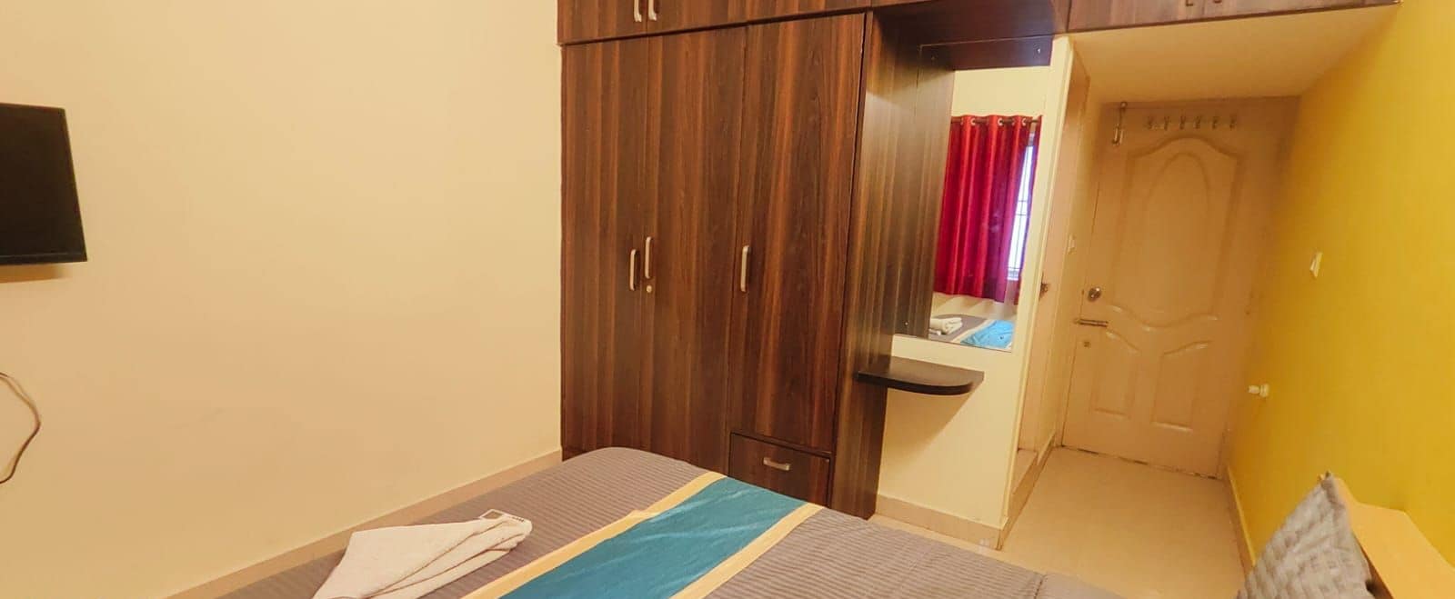 Une chambre à coucher avec un lit, une armoire, un miroir et une porte.
