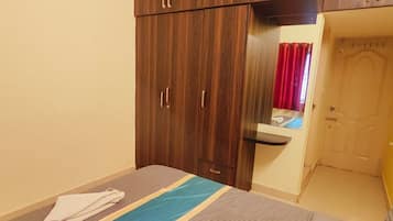 A bedroom with a bed, a wardrobe, a mirror, and a door.