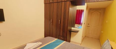 Une chambre à coucher avec un lit, une armoire, un miroir et une porte.