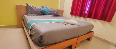 Una cama con una colcha gris y azul, una almohada y un control remoto encima.