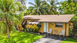 Ein gelbes Haus mit Ziegeldach, einer Veranda mit zwei weißen Stühlen und der Hausnummer 4420 an der Wand.