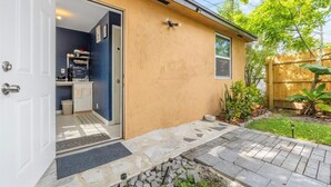 Ein Haus mit geöffneter Garagentür, durch die eine Küche mit Arbeitsplatte und Schränken zu sehen ist.