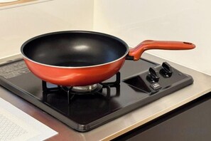 A red frying pan on a black induction cooktop. - YOSHIFUSA TOKYO (Tokyo)