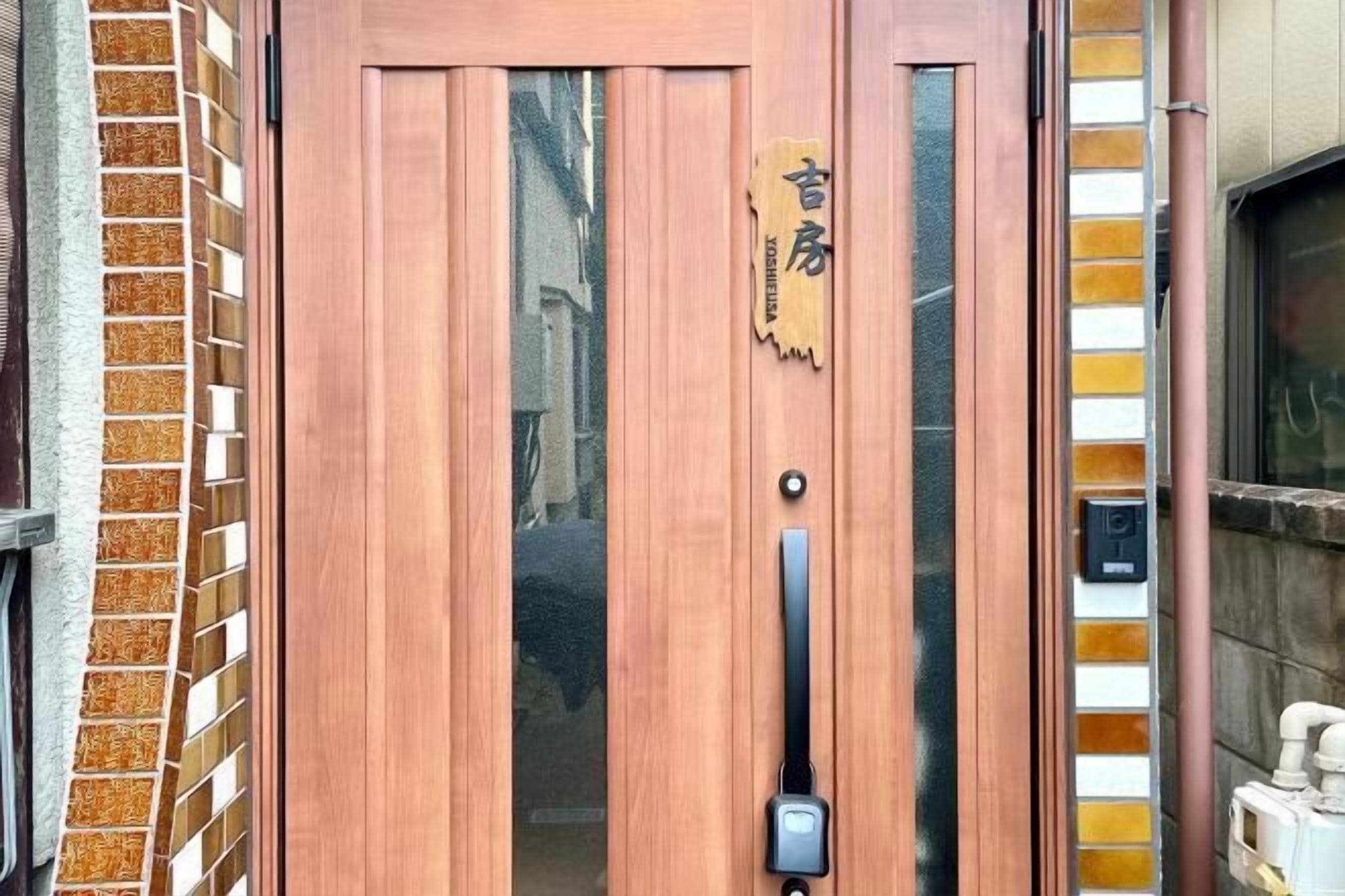 A wooden door with a nameplate reading "YOSHIEIYA" and a modern doorbell.