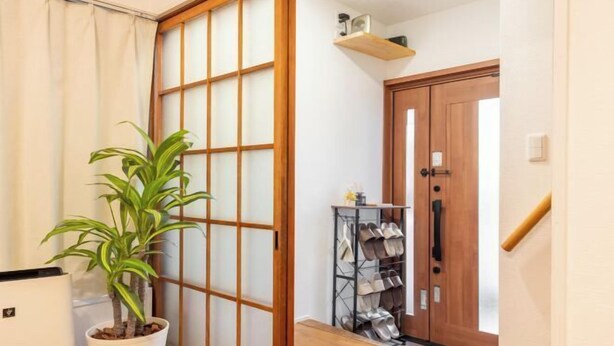 A hallway with a sliding shoji screen, a potted plant, a shoe rack, and a wooden door. - YOSHIFUSA TOKYO (Tokyo)