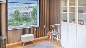 A room with a large window, a small stool, a chair, and a cabinet with glass doors. - Gorgeous home in Broager with WiFi (Broager)