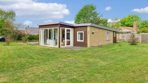 A modern single-story house with a glass-enclosed patio, a brick exterior, and a well-maintained lawn. - Gorgeous home in Broager with WiFi (Broager)
