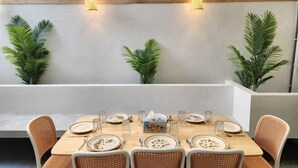 A dining area with a long table set for six, surrounded by wicker chairs. There are two wall-mounted light fixtures above the table. - Petaling Jaya 5 BedRoom Landed SS17/ for up to 18pax/Jaya1/Phileo/UM (Petaling Jaya)