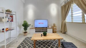 A modern living room with a TV displaying 'NETFLIX', a wooden coffee table, a patterned rug, a bookshelf with toys, and a potted plant. - Petaling Jaya 5 BedRoom Landed SS17/ for up to 18pax/Jaya1/Phileo/UM (Petaling Jaya)