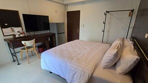 A hotel room with a bed, a desk with a chair, a television, and a wardrobe. - J.K. Mansion (Bangkok)
