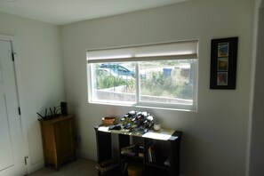 A room with a desk, a window with blinds, a door, and a small cabinet.