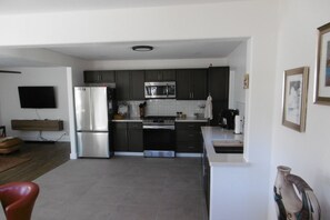 A modern kitchen with dark cabinets, a stainless steel refrigerator, a microwave, and a coffee maker.
