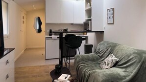 Ein kompakter Wohnbereich mit Küchenzeile, einer Couch und einem kleinen Tisch.
