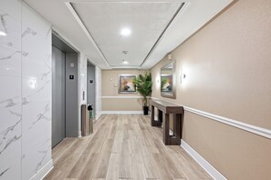 Un pasillo con suelo de mármol, un banco de madera y una planta en maceta.