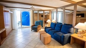 Un amplio salón con un sofá azul, muebles de madera y un ventilador de techo.