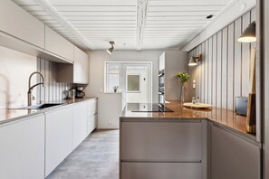 A modern kitchen with white cabinetry, a wooden countertop, and a built-in stove.