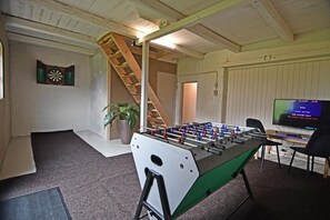 A room with a foosball table, a dartboard, and a television. - Cosy and modern house in peaceful setting (Otterup)