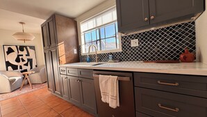 A modern kitchen with dark cabinetry, a tiled backsplash, and a window above the sink. - Amazing Condo In Downtown Alhambra, 20 minutes to DTLA, 10 minutes to Pasadena (Alhambra)