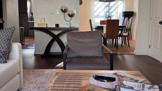 A modern living room with a sofa, a coffee table with books, a dining area with a chandelier, and a kitchen in the background. - Amazing Condo In Downtown Alhambra, 20 minutes to DTLA, 10 minutes to Pasadena (Alhambra)