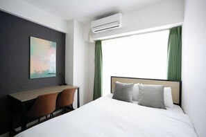 A hotel room with a bed, a desk, two chairs, an air conditioner, and a window with green curtains. - Daffitto Mitaka (Mitaka)
