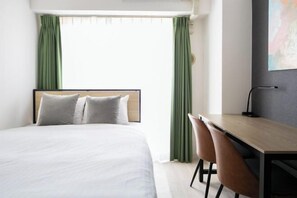 A hotel room with a bed, a desk, two chairs, and a window with curtains. - Daffitto Mitaka (Mitaka)