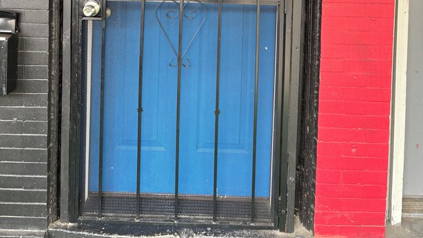 A blue door with a metal gate, a number plate, and a decorative plate with text. - 1 bedroom apartment across from Temple Hospital (Philadelphia)