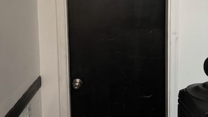 A closed black door with a silver handle, white trim, and a small window at the top. - 1 bedroom apartment across from Temple Hospital (Philadelphia)