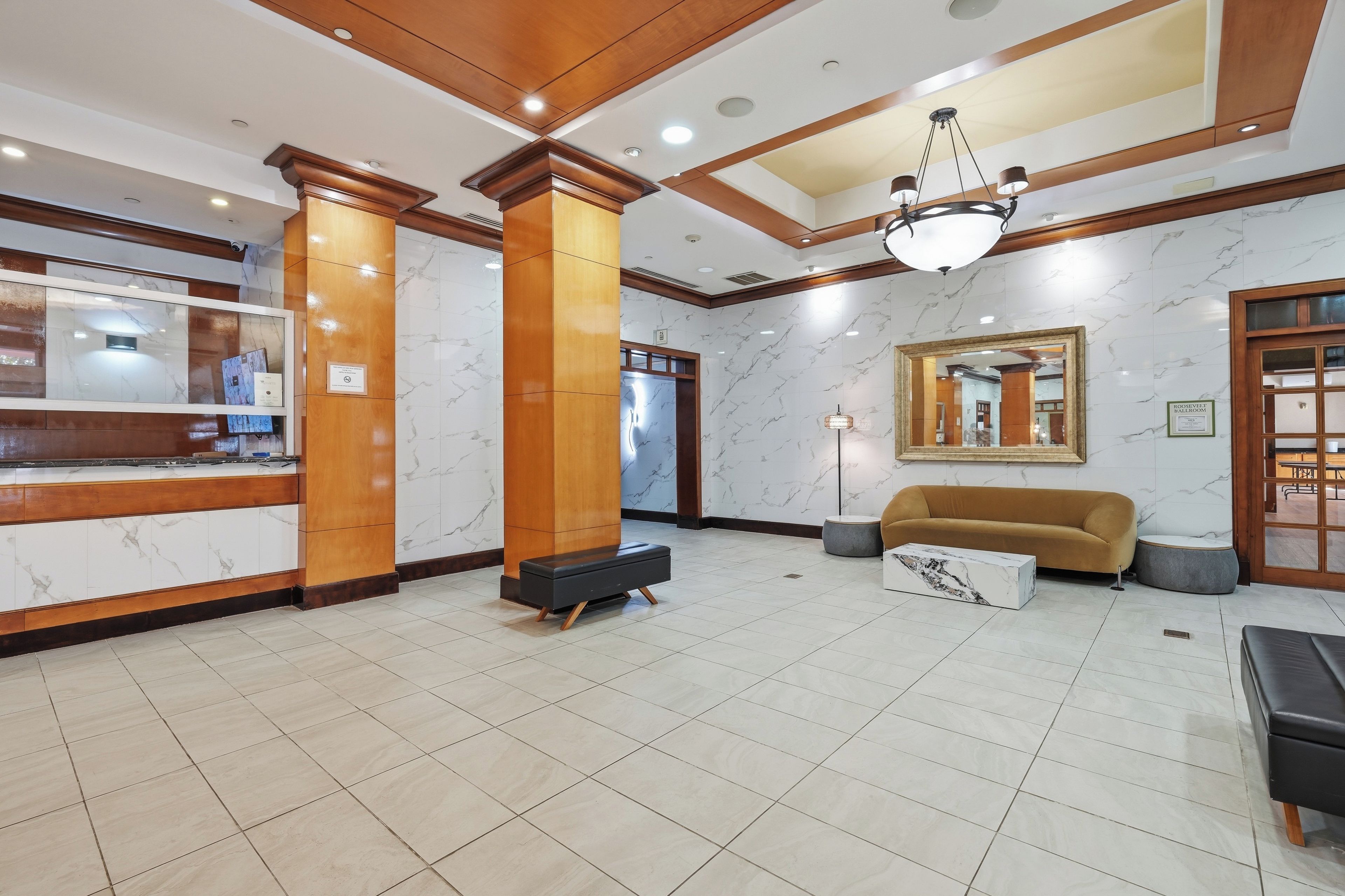 A hotel lobby with a reception desk, a sofa, a coffee table, and a chandelier.