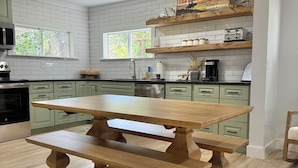 A kitchen with a wooden table, white tiled backsplash, and green cabinets. - 100 year old Montana Cottage! (Manhattan)