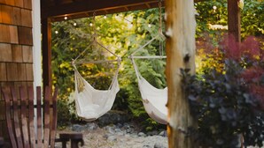 A wooden deck with two white hammocks suspended from a wooden structure.