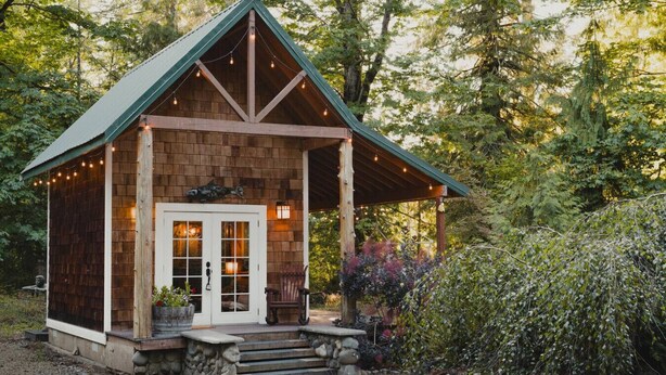 A rustic cabin with a wooden exterior, a porch, and a stone staircase leading to the entrance.