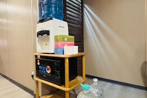 Un distributeur d’eau, une machine à café et une petite table avec une bouteille d’eau et un gobelet en plastique.