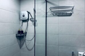 Une douche équipée d’un pommeau de douche à main, d’un porte-serviettes mural et d’un distributeur de savon.