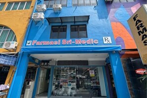 Une devanture de magasin avec une enseigne indiquant « Farmasi Sri-Medic » et un symbole de pharmacie.