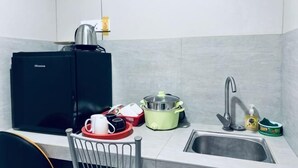 A kitchen with a black refrigerator, a sink, a kettle, a green slow cooker, and a coffee maker. - All-You-Need Room for 4 Walk & Drive Around to Tourist Hotspot Eden (Melaka)
