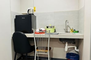 A compact kitchenette with a sink, a small stove, and a chair. - All-You-Need Room for 4 Walk & Drive Around to Tourist Hotspot Eden (Melaka)