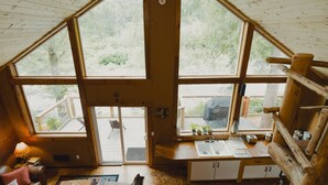 A cabin with a kitchen area, large windows, and a deck.