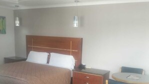 A bedroom with a bed, bedside table, and a small round table with a chair.