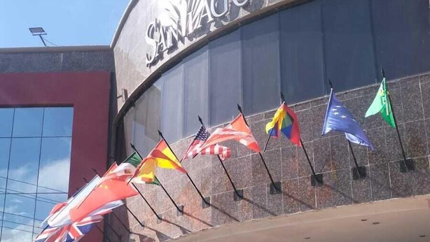 A building with the sign "SANAGO" and multiple flags displayed outside.