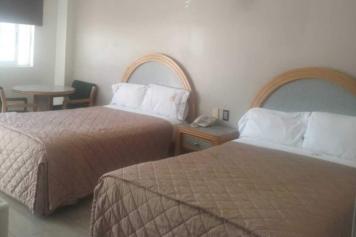 Ein Hotelzimmer mit zwei Betten, einem kleinen Tisch und einem Stuhl.