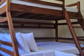 Un llit superposat amb roba de llit blanca i estructura de fusta.