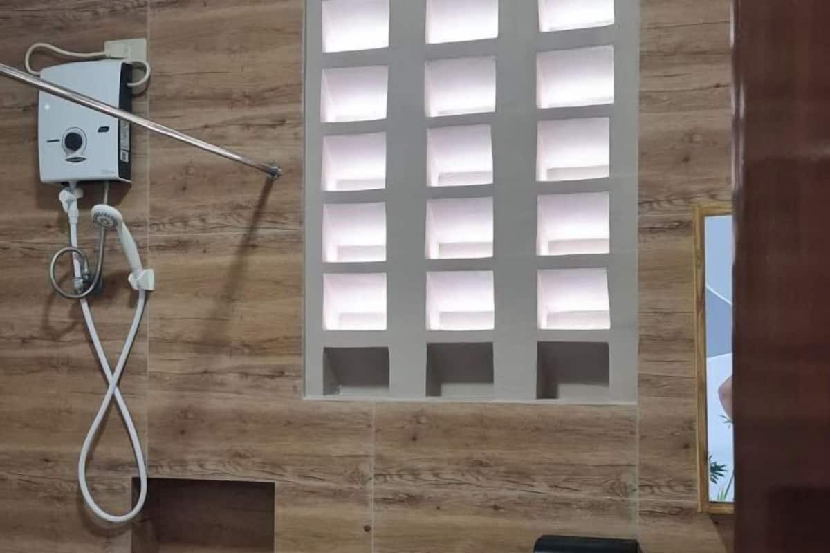 Un espace douche avec un mur en bois, une pomme de douche blanche et un panneau de commande.