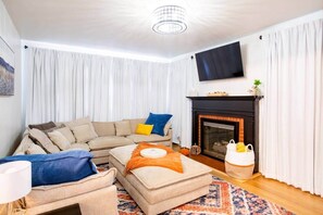 A living room with a sofa, ottoman, and a fireplace.