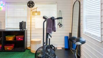 Un gimnasio en casa con equipo de ejercicio, un reloj y estanterías.